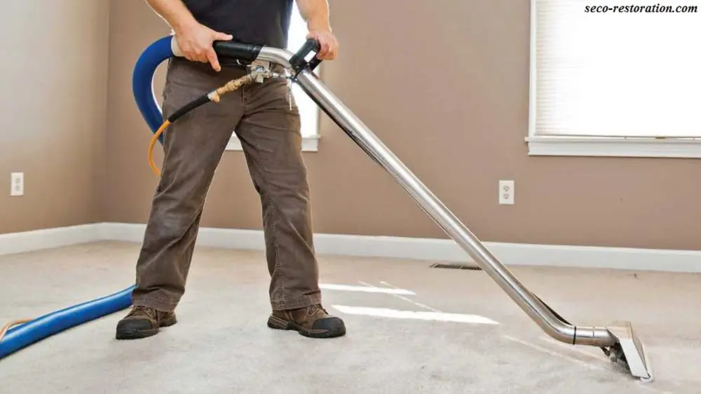 Stained wall base above lifting wood flooring after water damage