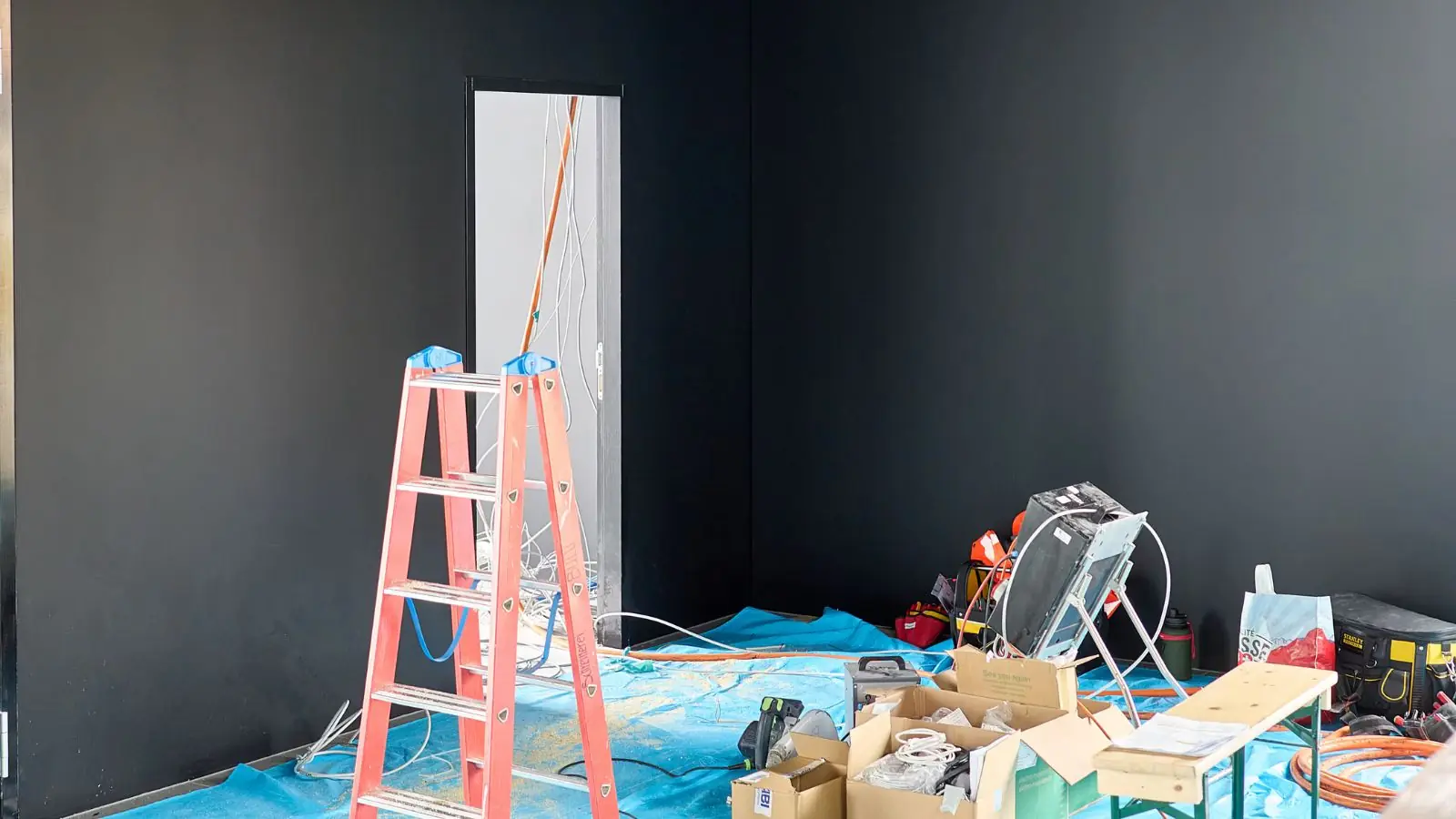 Room prepared for repairs with plastic sheeting, a ladder and drying equipment